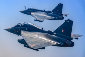 The image shows a Tejas Mk-1 trainer flying alonside a Tejas single-seat fighter