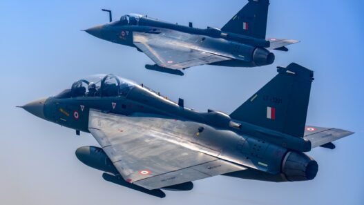 The image shows a Tejas Mk-1 trainer flying alonside a Tejas single-seat fighter