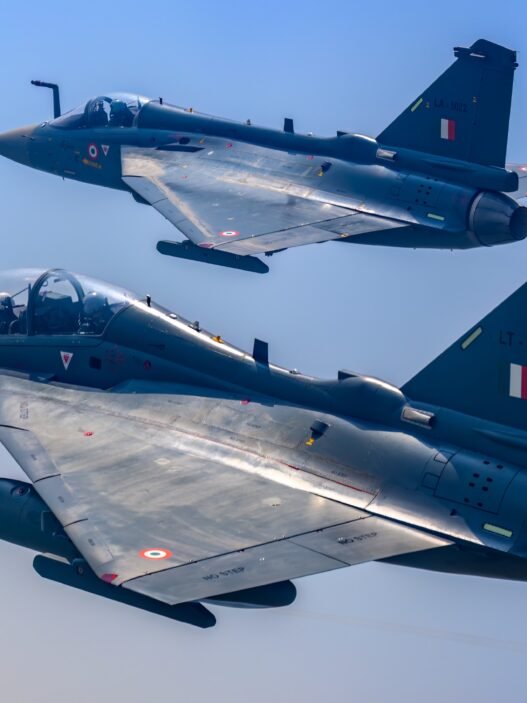 The image shows a Tejas Mk-1 trainer flying alonside a Tejas single-seat fighter